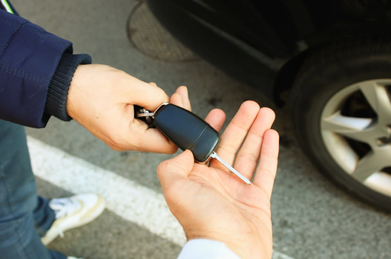 a person handing a car key to a junk car buyer