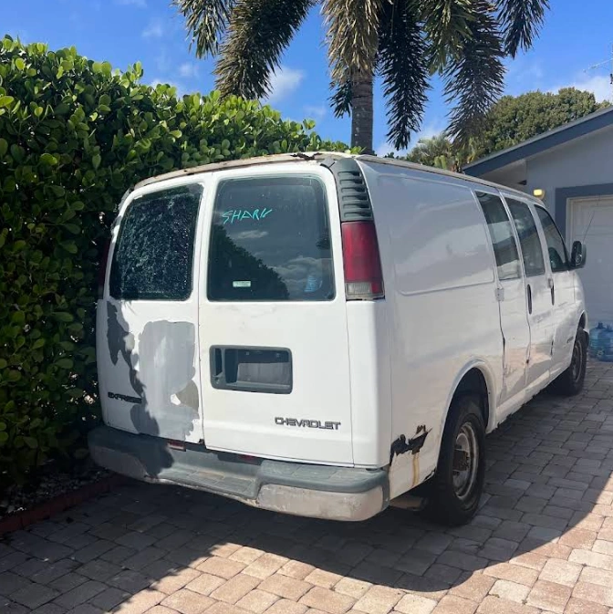 We Buy Vans For Cash in Florida. A used white Chevrolet Express cargo van parked on driveway.