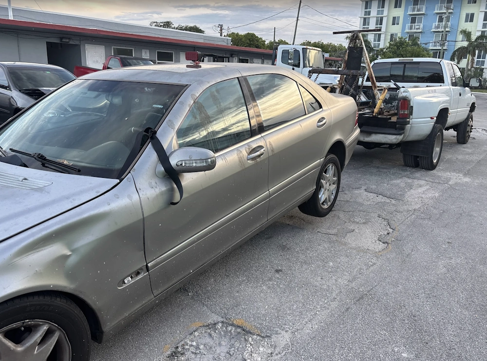 A damaged silver sedan being towed by Hercules who buy junk cars without title in Deerfield Beach FL