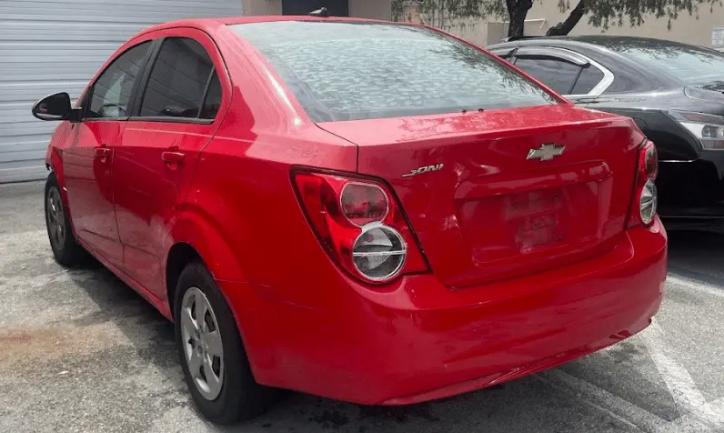 Red Chevrolet Sonic sedan parked in a lot promoting Miramar Junk Car Buyer