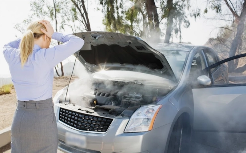 Woman standing beside a smoking car with an open hood, representing services that buy cars with blown engines in Fort Lauderdale.