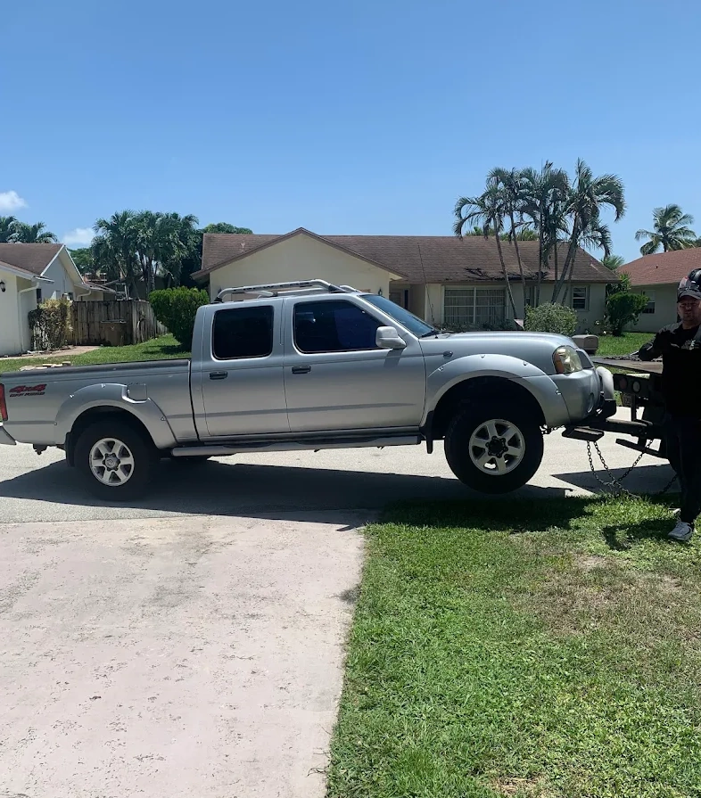 Silver pickup truck being towed representing Hercules We Buy Junk Cars Lauderhill services