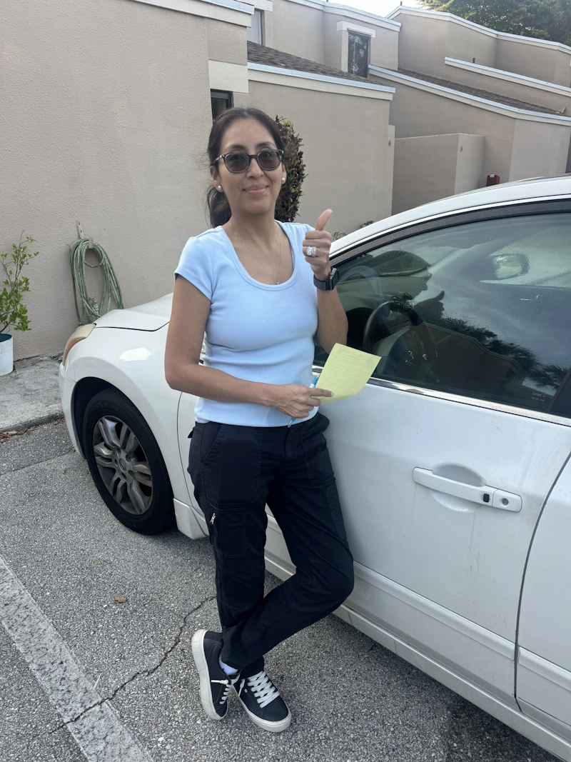 A woman gives a thumbs up while holding a bill of sale after using a service to sell my junk car in Boca Raton.