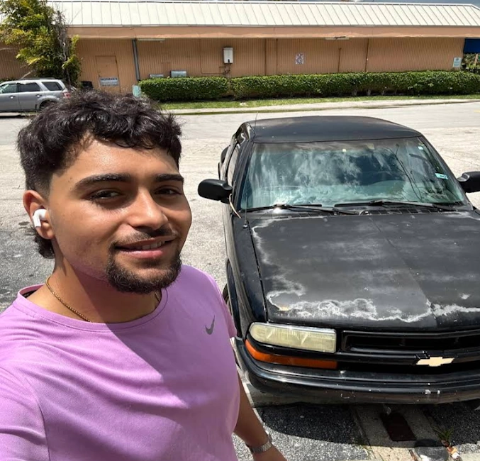A man standing next to a black Chevrolet vehicle for a cash for old Chevy SUV in Pompano Beach transaction.