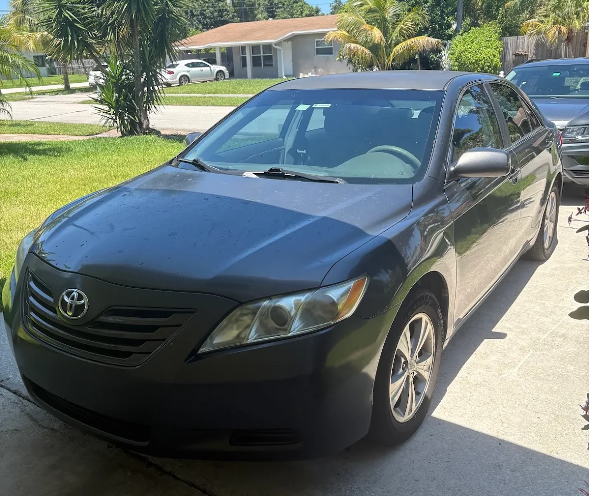 Toyota Camry sedan parked on a driveway, representing options to sell car not in my name Florida.