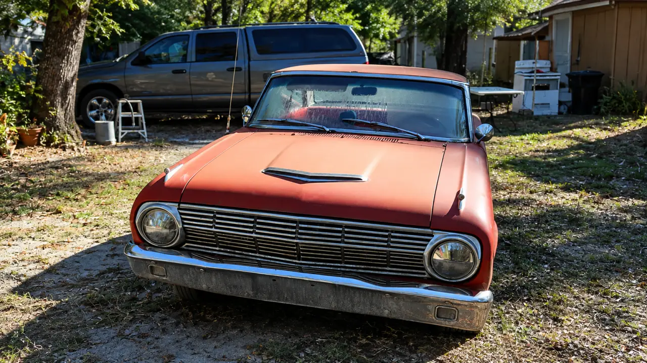 Vintage red car parked in a residential yard, illustrating how to sell a car of a deceased person in Florida.