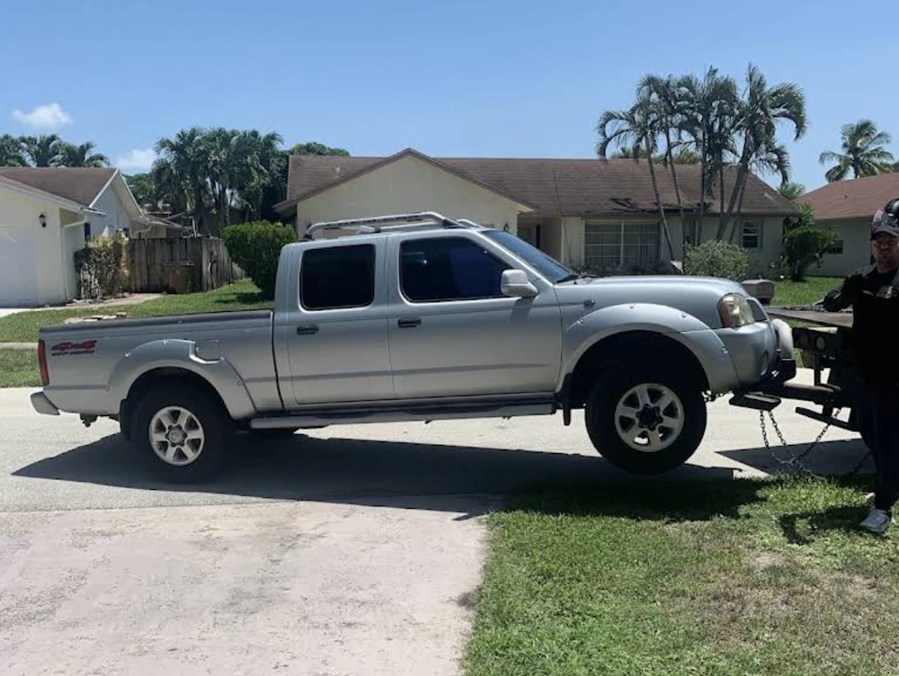 Junk Car Buyer in Plantation, FL loading a silver pickup truck onto a tow bed for cash removal.